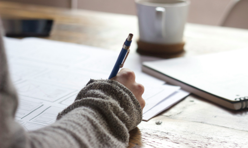 Hand holding pen and writing on paper